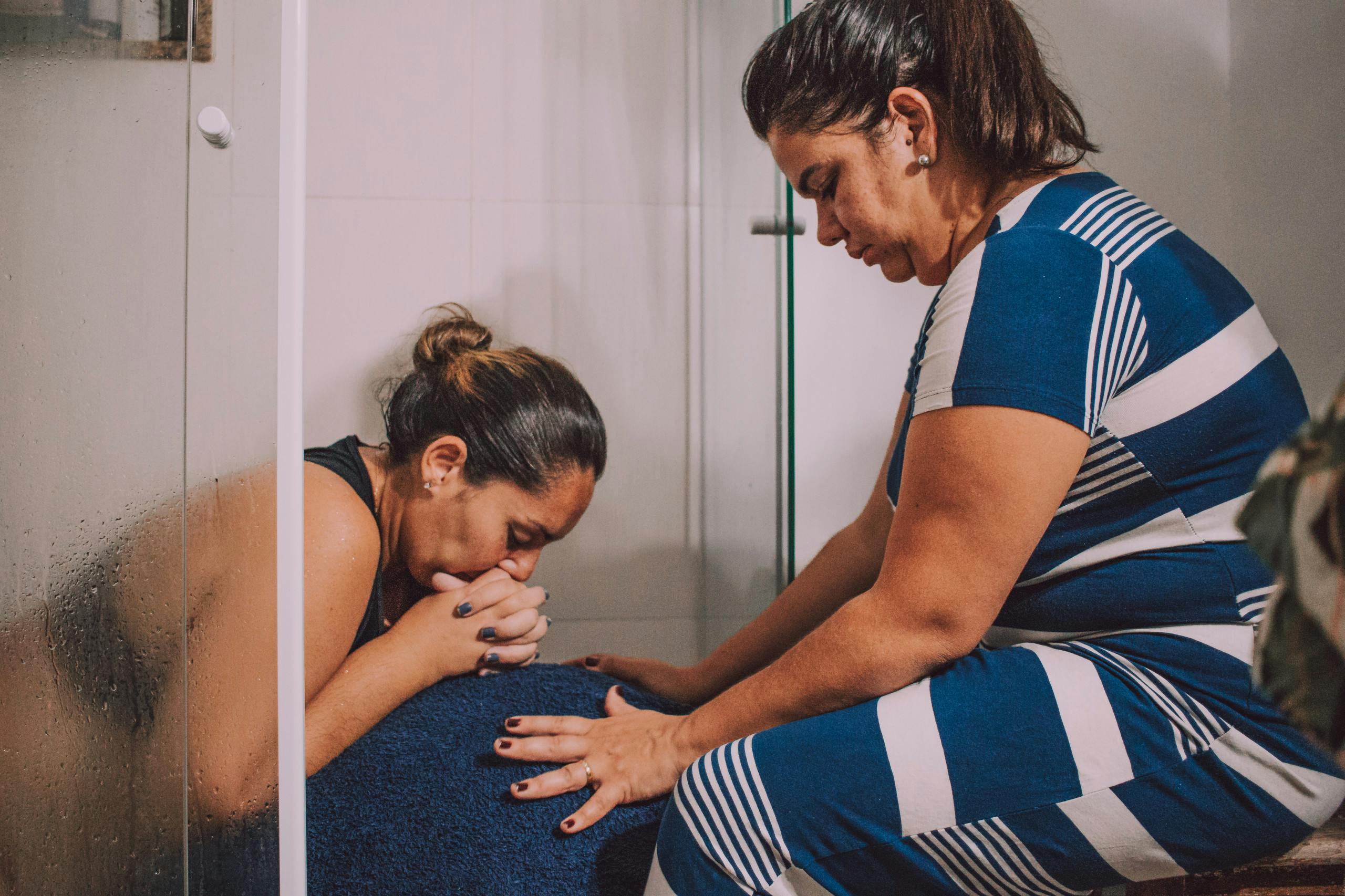 Emotional support during labor in a bathroom setting with a doula.