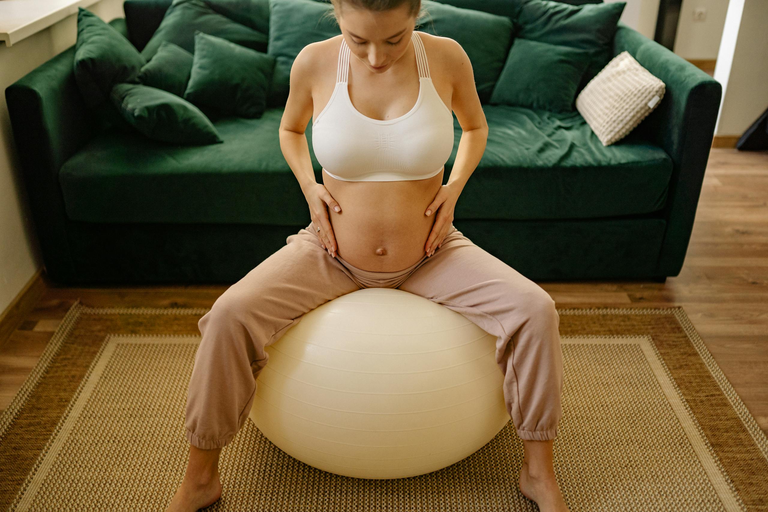 Expectant mother practicing prenatal exercises with a yoga ball at home, emphasizing fitness and well-being.